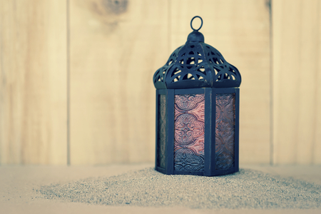 Design metal lantern on sand over blurred wood background, vintage tone styleの写真素材