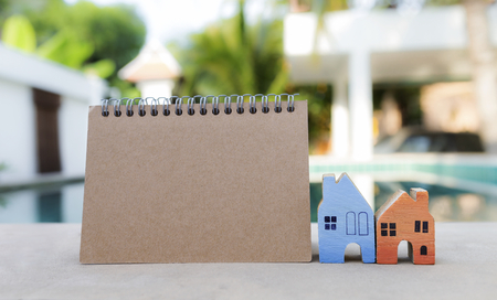 Real estate concept, blank brown card and colorful miniature house over blurred house backgroundの写真素材