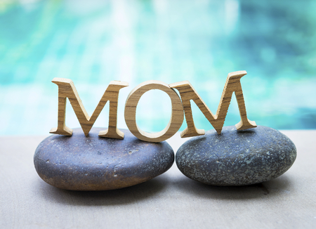 Mom wooden text on spa stone over blurred blue swimming pool backgroundの写真素材