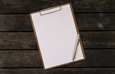 Blank paper on wooden clipboard on vintage dark wooden floor backgroundの写真素材