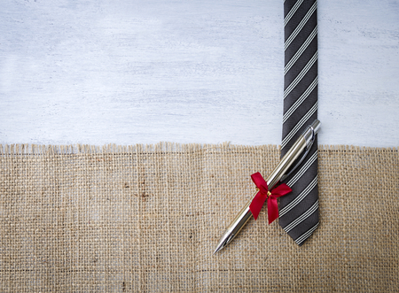 Pen on black necktie with space on hessian fabricの写真素材