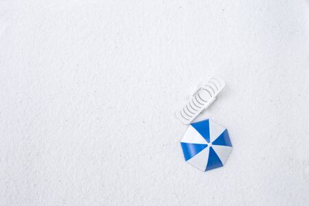 Blue and white umbrella and white plach chair with space on white sand backgroundの写真素材