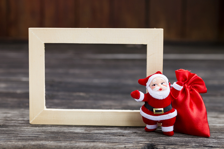 Christmas concept, Santa Claus with red bag over empty wood frameの写真素材