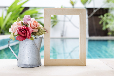 Rose paper flower in tin pot with wooden frame over blurred swimming pool, outdoor day lightの写真素材