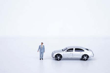 Miniature business man with model car on white background, business conceptの写真素材