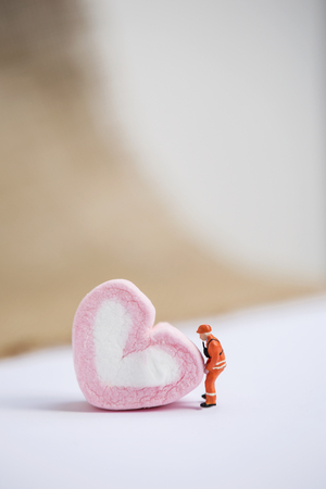 Miniature worker movie pink heart shape marshmallow over blurred background, love and valentine concept backgroundの写真素材