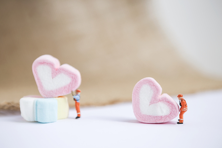 Valentine concept background of worker moving pink marshmallow heart, building loveの写真素材