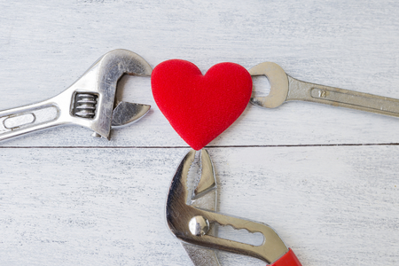 Heart repair concept, red heart with tool on white wood background, fixing heartの写真素材