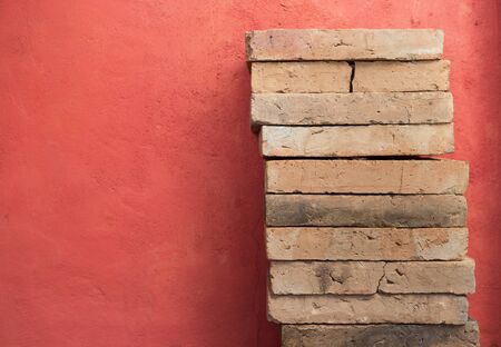 Clay brick stack over red cement wall background, construction conceptの写真素材