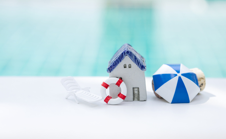 Miniature beach house concept, summer holiday home, miniature house and beach set over blurred blue water backgroundの写真素材