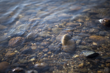 Nature concept background of closeup blurred stone in the clear river water with sunset light, peaceful and cooling conceptの写真素材