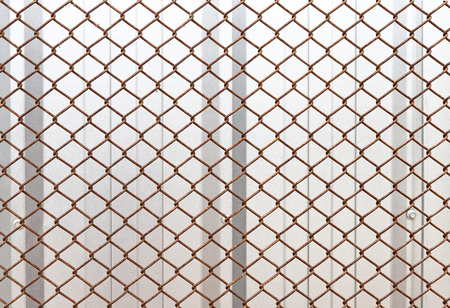 Closeup rusty steel mesh metal fence to protect house, construction concept, safety backgroundの写真素材