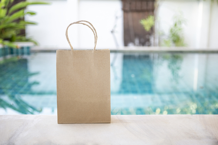 Brown paper bag over blue swimming pool background, blank paper bag