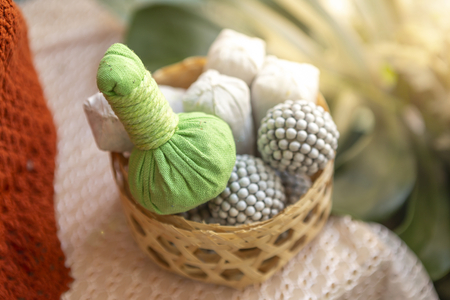 Green herbal massage ball in bamboo basket over blurred background, vintage warm lightの写真素材