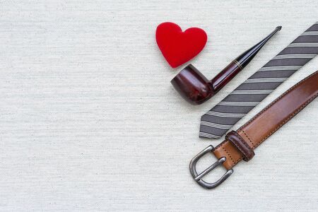 Antique design vintage smoking pipe with men necktie and leather belt with space on canvas fabric background, men object and fashionの写真素材