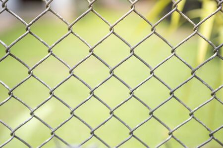 stainless Steel Chainlink fencings over blurred green garden background, outdoor day light, Metal Chain Link Fence Backgroundの写真素材
