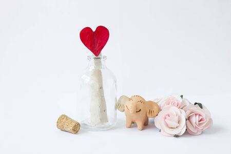 Message in open bottle with red heart paper with happy smiling elephant clay, happy romance love...