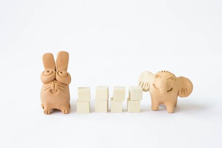 Cute little elephant and rabbit clay doll with wooden cube isolate on white background