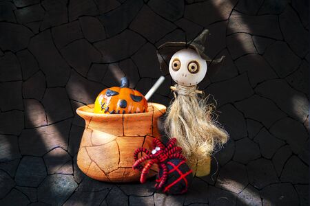 Halloween concept background, Cute little wooden witch doll with black and red yarn spider with halloween pumpkin in clay pot over abstract brick wall background, decorate itemの写真素材