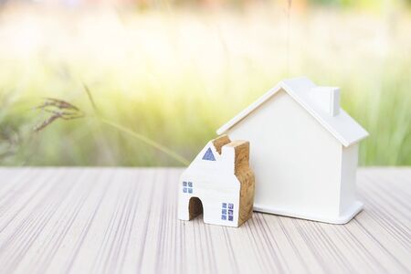 Miniature wooden house and wooden hosue model over blurred green garden background, outdoor day light, new hosue, home and property business conceptの写真素材
