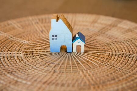 Small house on rattan tray, miniature wooden house with small model house on wood texture...
