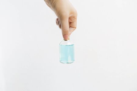 Girl hand holding ethanol alcohol in glass bottle with space on white background, hygiene and...
