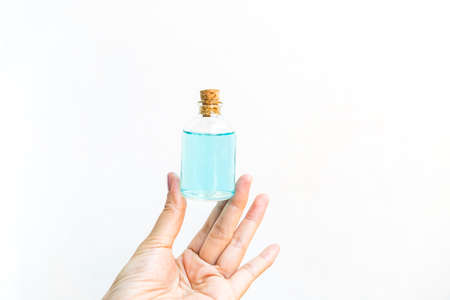Alcohol gel in glass bottle in girl hand on white background, hand sanitizer, covid 19 cleaning gelの写真素材