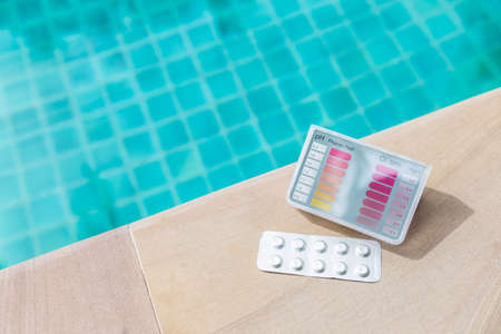 Pool tester test kit and tablets on swimming pool edge, summer outdoor day light, water quality testing, quality test kit for swimming pool waterの写真素材