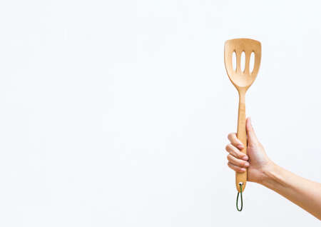 New wooden ladle in girl hand with space on white background, kitchen equipment, product from natureの写真素材
