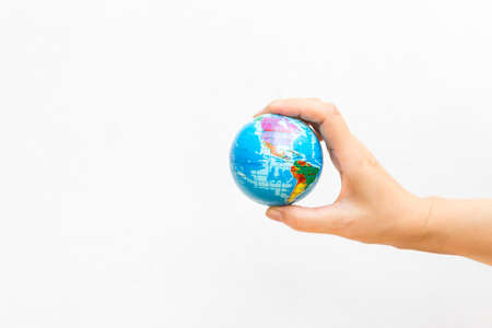 World map foam Earth Globe stress relief bouncy ball in girl hand on white background, world news or environmentalの写真素材