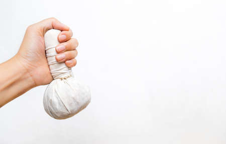 Herbal massage ball in girl hand on white background, handmade Thai style heat ball filled with variety of herbs, spa productの写真素材
