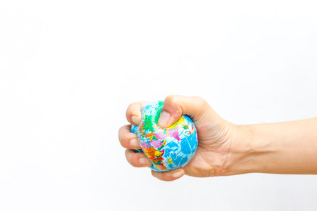 Global stress ball in girl hand on white background, squeeze the worldの写真素材