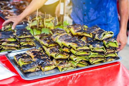 Traditional thai food grill marinate fish wraping with banana leaves, food market in Thailand, local food marketの写真素材