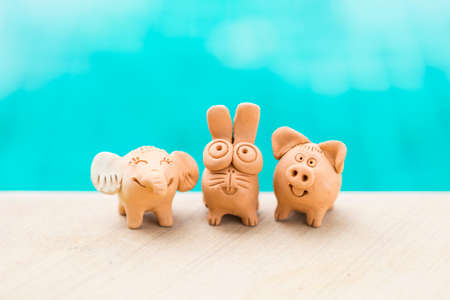 Happy animal clay friend over blurred blue water background, safe animal, cute little elephant with rabbit and pig clay, garden decoration itemの写真素材