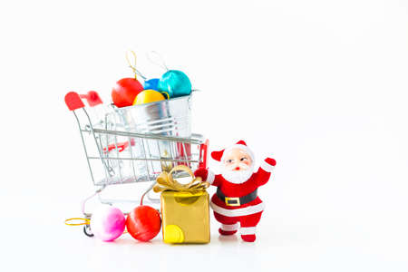 Christmas concept background, Santa doll and gift box with colorful ball for decoration in shopping cart on white backgroundの写真素材