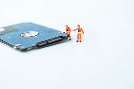 Miniature worker with hard disk on white background, computer service and maintenance business conceptの写真素材