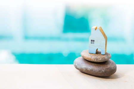 Blue wooden house model on stack of stone over blurred blue water background, property business concept, new houseの写真素材