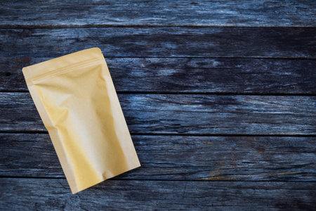 Blank craft paper bag on dark wooden background, dry food and sweet packagingの写真素材