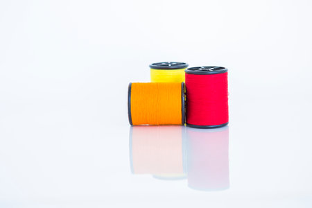 Red and orange thred spool on white background, craft and sewing equipmentの写真素材