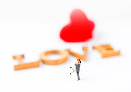 Miniature couple over blurred love font and red heart background, love and romance concept, valentine background ideaの写真素材