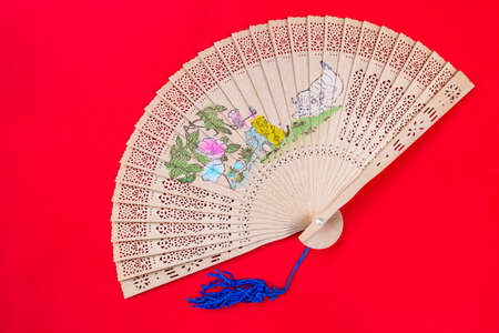 Chinese wooden foldable fan on red background, Asian style hand fan, design wooden hand fanの写真素材