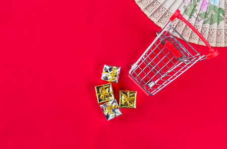 Empty shopping cart with silver and golden gift box on red fabric background, Chinese new year shopping, selective focusの写真素材