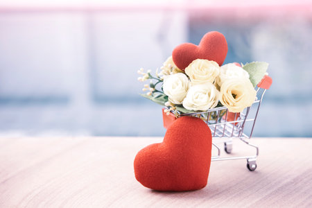 Red heart with flower in shopping cart over blurred background, valentine card background idea, love and romance concept, vintage tone styleの写真素材