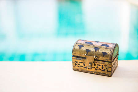 Vintage style wooden treasure box with space on blurred blue water background, selective focus, hidden treasureの写真素材