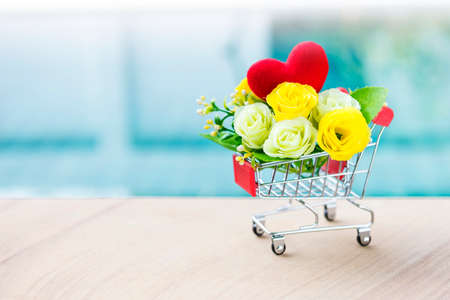Rose flower in shppping cart over blurred blue water background, valentine card background idea, online dating, valentine giftの写真素材