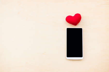 Smartphone and red heart with space on wood background, love message and call, valentine concept backgroundの写真素材