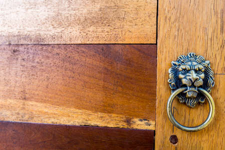 Antique look Lion shape door handle ring on wooden door background, door decoration designの写真素材