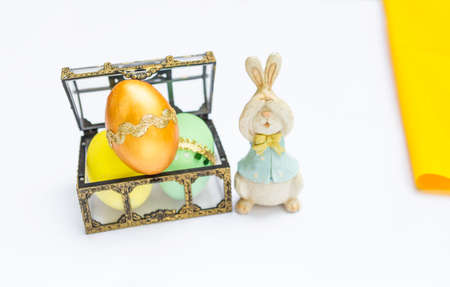 Golden easter eggs in treasure box with wooden rabbit on white background, happy easter card...