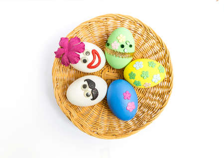 Colorful Easter egg design in round rattan basket isolate on white backgroud, colorful egg with flower and face design, funny easter conceptの写真素材