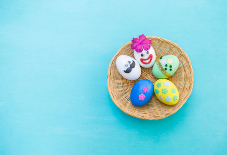 Beautiful Easter egg design on round rattan basket with space on blue background, funny easter egg...